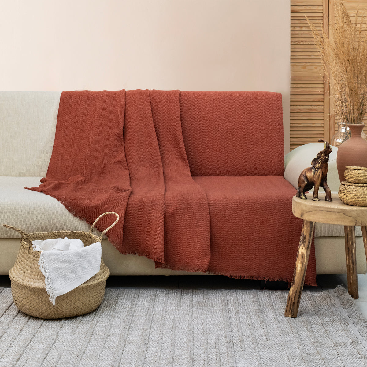 Merlin fringed cotton blend throw styled on a chair in a cosy living room